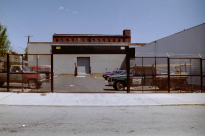 Expanded metal mesh welded steel fence with motorized roll down coiling gate and barbed wire for parking lot. (Brooklyn, NY)