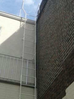 Simple steel fixed roof access ladder braced to building and widened at top. Fabricated in sections and thru bolted together upon installation for ease of positioning and loading to site. (Manhattan, NY)
