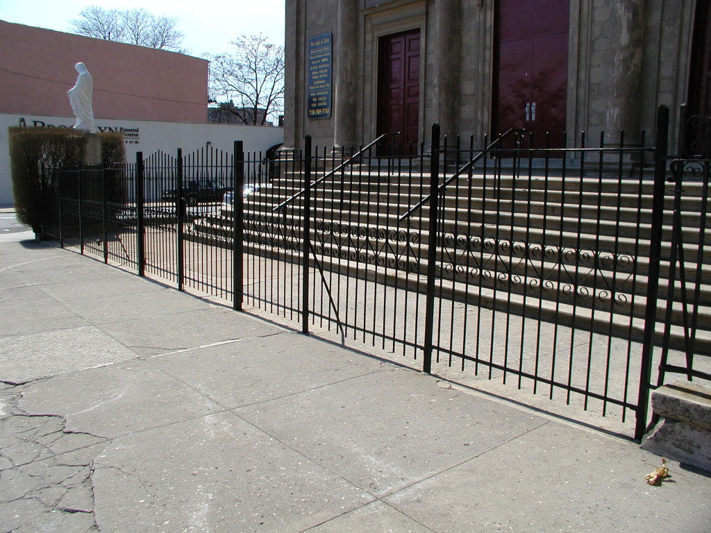 Simple 6′ welded steel bar fence with scalloped top and 2” tube steel